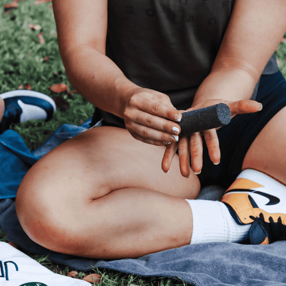 Athlete sanding down calluses on her hand with a pumice stone